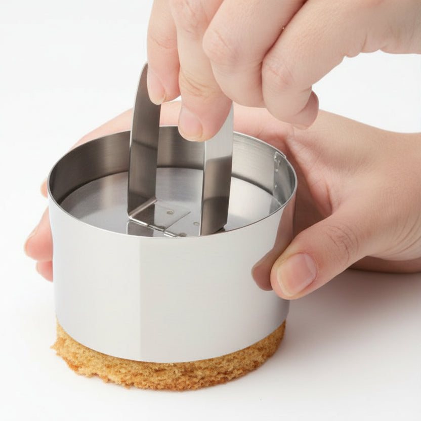 jest to rant do monoporcji ze stali nierdzewnej, trzymany jedną ręką a od dołu widać powoli wysuwające się ciasto. Druga ręka trzyma popychacz również ze stali nierdzewnej dzięki czemu łatwiej jest wypchnąć ciastko z rantu bez uszkadzania kształtu